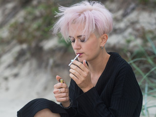 outdoor portrait of a beautiful sexy young woman with pink hair and shaved temples , smoking hipster girl