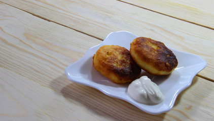 Frying homemade oats cottage cheese pancakes. Russian syrniki with jam and sour cream on wooden background. Traditional breakfast