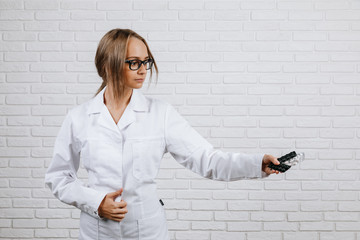 Doctor in black glasses in a white coat gives a variety of pills on a white background