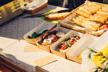 Bruschetes and sandwiches with mozzarella, dried tomatoes and pine nuts in paper plates on the counter in a street cafe