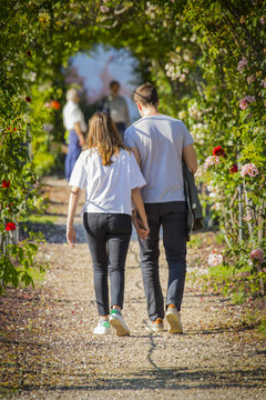 Vertical Image Of A Couple Of Boys Walking Jointly In A Rose Garden