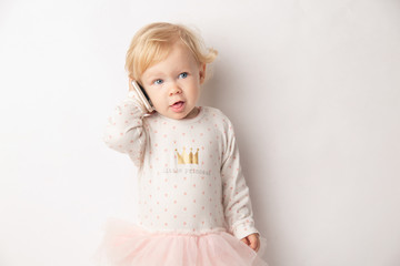 Little blond Girl with Mobile Phone Isolated on White Background. concept a new generation or children and technology