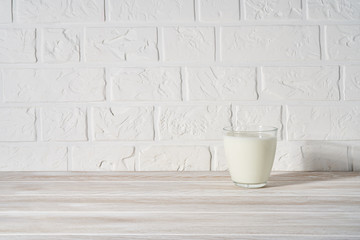 Glass of milk on white wooden background.