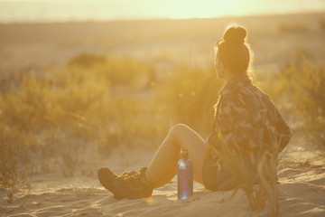 traveller woman with bottle of water sitting and looking into the distance