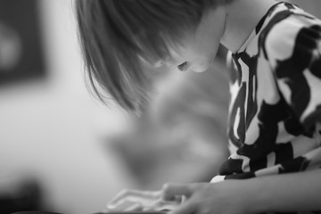 Long strands of hair covering the face of the boy playing on the tablet