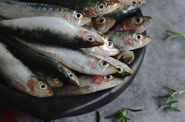 Sardines in black ceramic bowl over marble background. Top view.