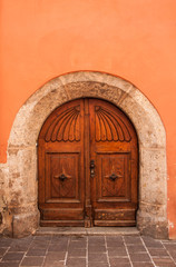 Fototapeta na wymiar old wooden door orange wall background and stone arch