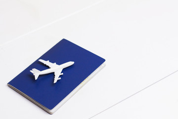 Plane travel concept, aircraft on blue passport on white wooden background