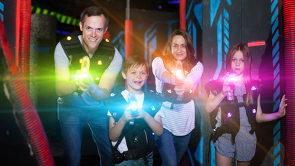 Obraz na płótnie Canvas Kids and adults in beams on lasertag arena