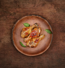Roasted chicken drumsticks with sesame on a plate on a wooden background