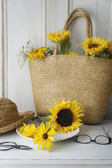Closeup of sunflowers in straw purse on table