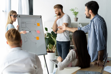 Developing new strategy. Two young colleagues conducting presentation while working with their...