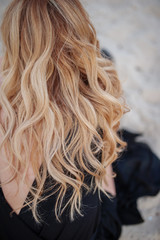 Beautiful ringlets of hair of the blonde in a black dress