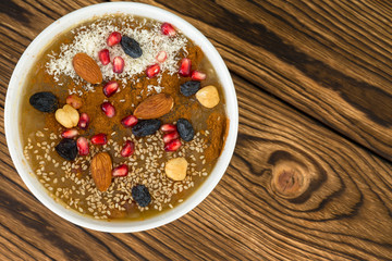 Bowl with sweet ashure against wooden background