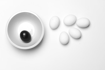 on a white background, white eggs and one black symbolizing diversity, separation, concretion and leadership