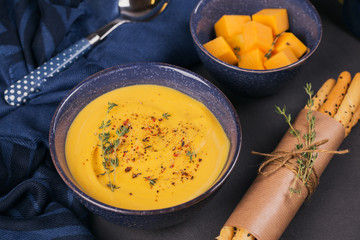 Pumpkin soup in blue bowl topped with fresh herb