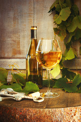 Bottle of white wine with glass on barrel