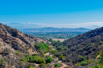 Fototapeta premium Suburbs in the distance with mountain hiking trails and room for text in sky