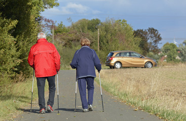 ein paar geht mit wanderstöcken auf einem feldweg