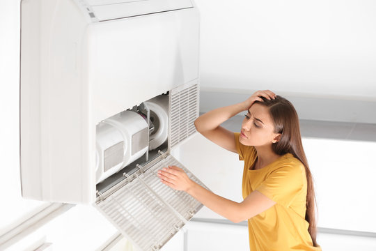 Young woman fixing air conditioner at home