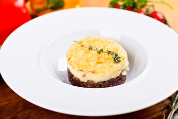 Shepherd's pie. Traditional British dish with minced meat, mashed potatoes and cheese on white plate. Close up