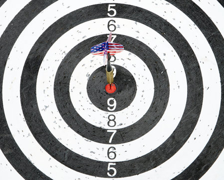 A dart with USA flag on the fletching hits the center circle of a target