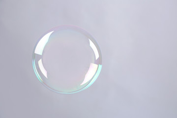 Beautiful translucent soap bubble on grey background. Space for text