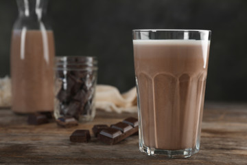 Glass of chocolate milk on wooden table, closeup. Space for text