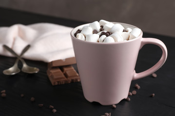 Tasty hot chocolate with milk and marshmallows in cup on table