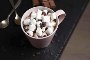 Fototapeta na wymiar Tasty hot chocolate with milk and marshmallows in cup on table