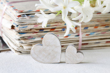 Two wooden hearts, stack of vintage letters and hyacinth flower.