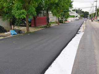 Fresh asphalt road in a development project has got already half of its surface repaired