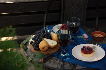 Fruits, cakes and two glasses of wine.