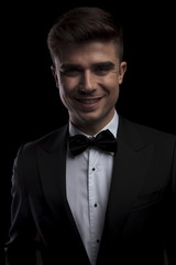 portrait of joyful young man in black tuxedo smiling