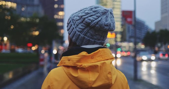 Portrait of Woman Standing on the Wind in Big City. SLOW MOTION 4K. Young Woman in Berlin waiting near the busy road. Breeze is playing with girls hair. Stormy weather, autumn, winter, spring.