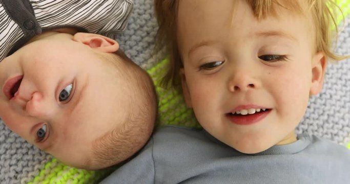 Children funny portrait little brother and sister cheek to cheek. Boy and newborn are lying top view close up