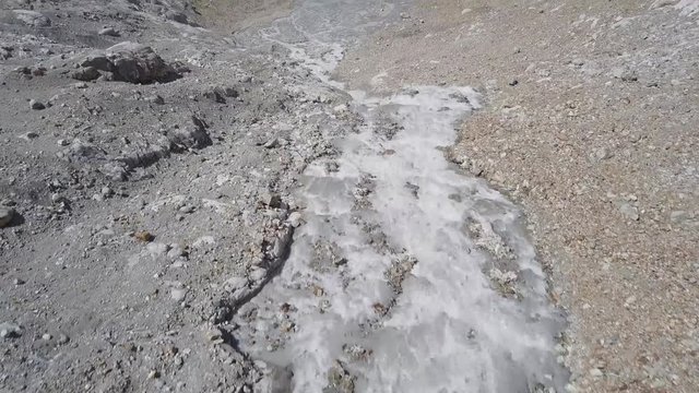 Flight along a glacier stream towards a mountain lake.