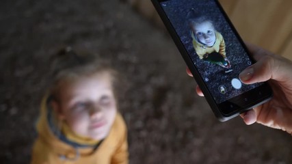 From top mother take smartphone pictures of child girl daughter holding feeding a parrot bird