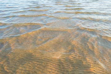 Soft wave of the water on the sandy beach. Waves of sand under the water