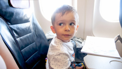 Portrait of cute 2 years old toddler boy flying in airplane