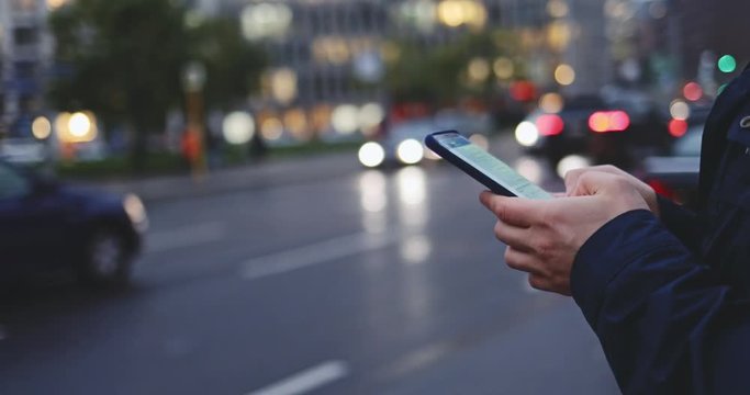 Young Man Hands Using Smartphone in the City. SLOW MOTION 4K. Unrecognizable Man using cell phone app, standing on busy street during rush hour traffic. Social network, planning, communicating.