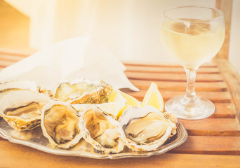 Raw oysters shells plate and glass of white wine, toned