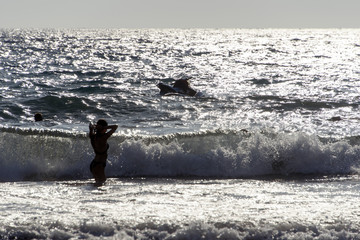 People playing, swimming in the waves in the island of Patmos, Greece in summer time