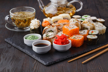 Sushi rolls, maki, nigiri Set served for two on black stone slate on dark background