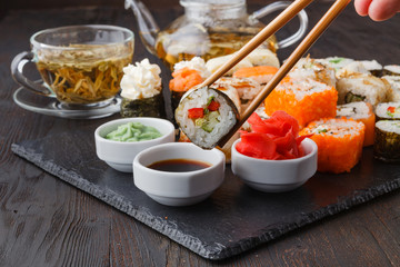 Fototapeta na wymiar Hand holding sushi Salmon roll in chopsticks with copy space for design work