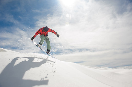 Jumping snowboarder keeping hand on the snowboard on the amazing background