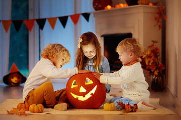 Fototapeta premium Kids carving pumpkin on Halloween. Trick or treat.