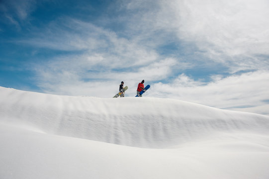 Two young snowboarders standing on the hill with the snowboards