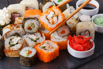 Female hand holding wooden sticks Philadelphia roll with salmon