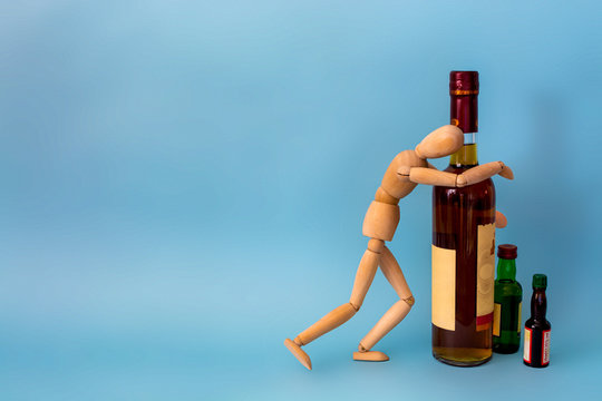 wooden man with many empty beer bottles. concept of alcoholism